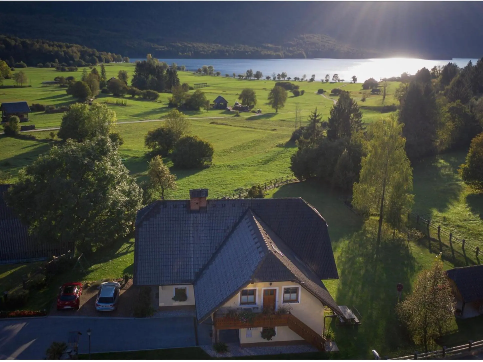 Naša hiša od zgoraj, za njo travniki in Bohinjsko jezero