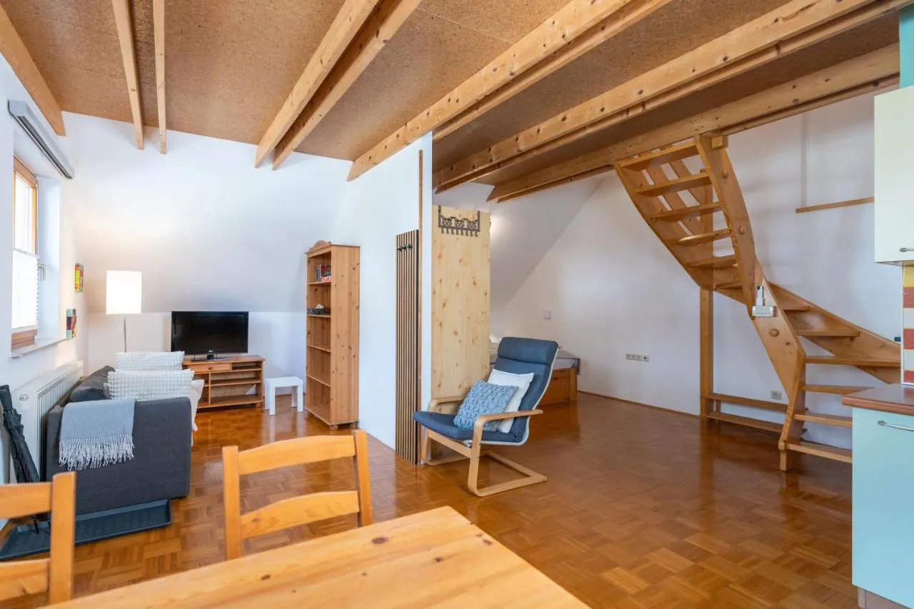 Dnevni prostor Apartmaja Studio z lesenimi stopnicami na galerijo